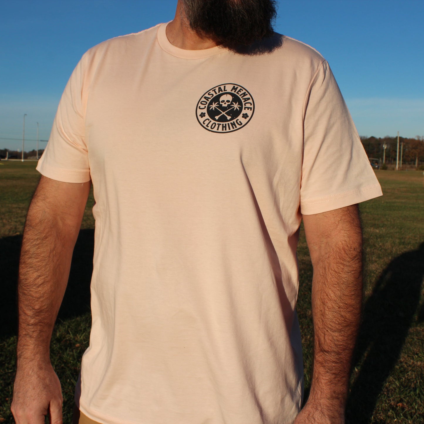 Men’s front view of the Coastal Menace Base Threat pink tee with small chest logo.
