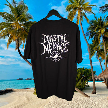 Black t-shirt with 'Coastal Menace' metal lettering design against a tropical beach background