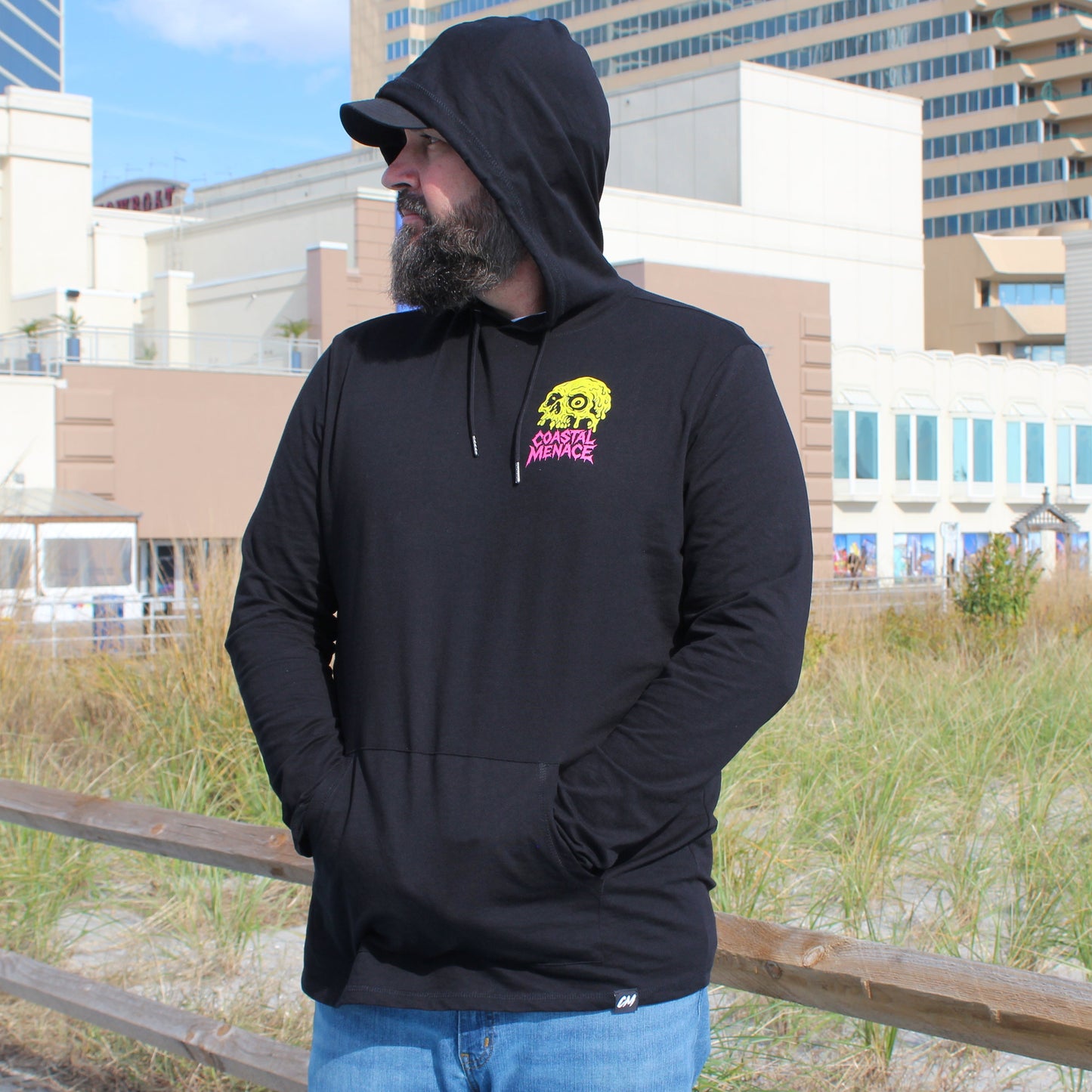 Man wearing a black hoodie with a logo in an urban setting