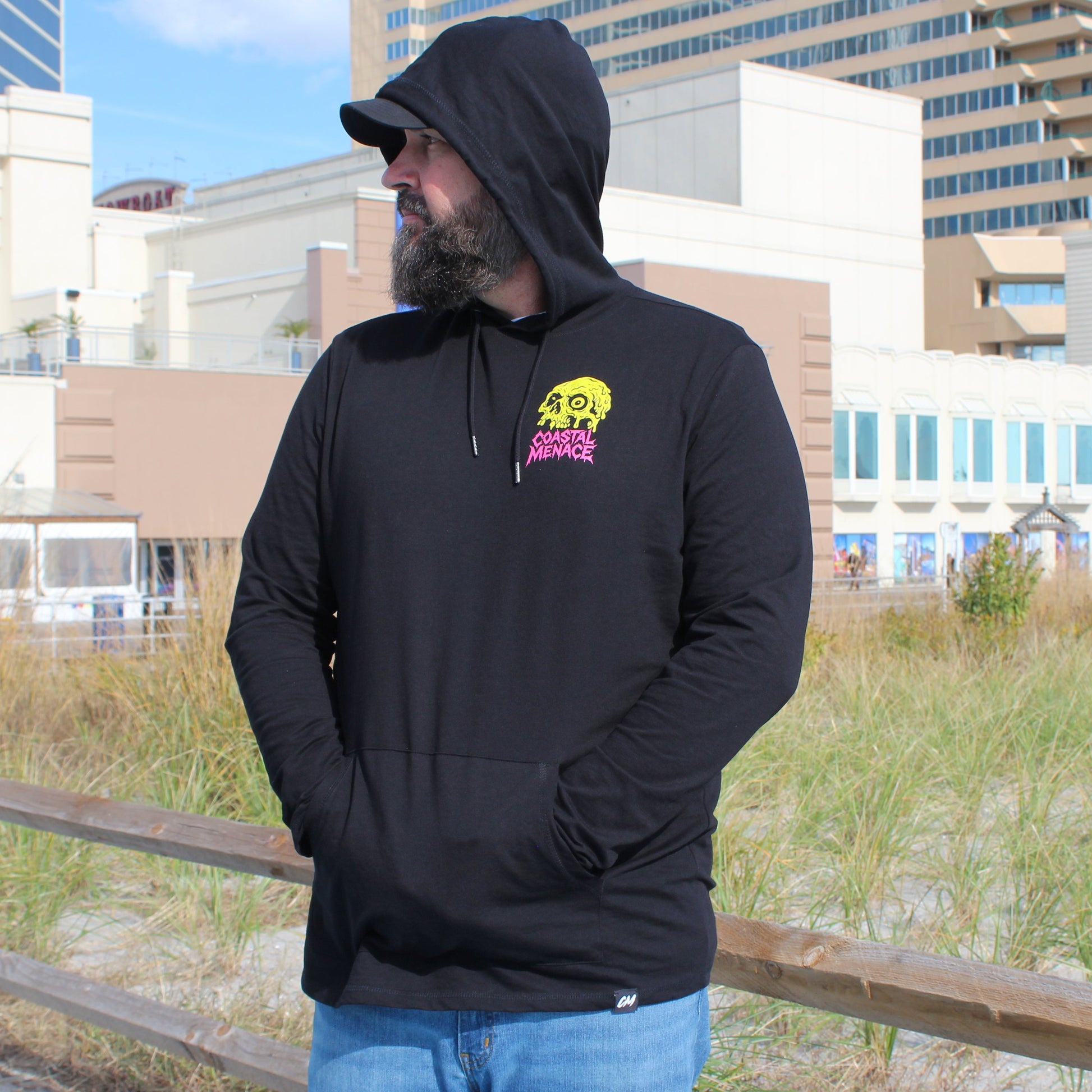 Man wearing a black hoodie with a logo in an urban setting