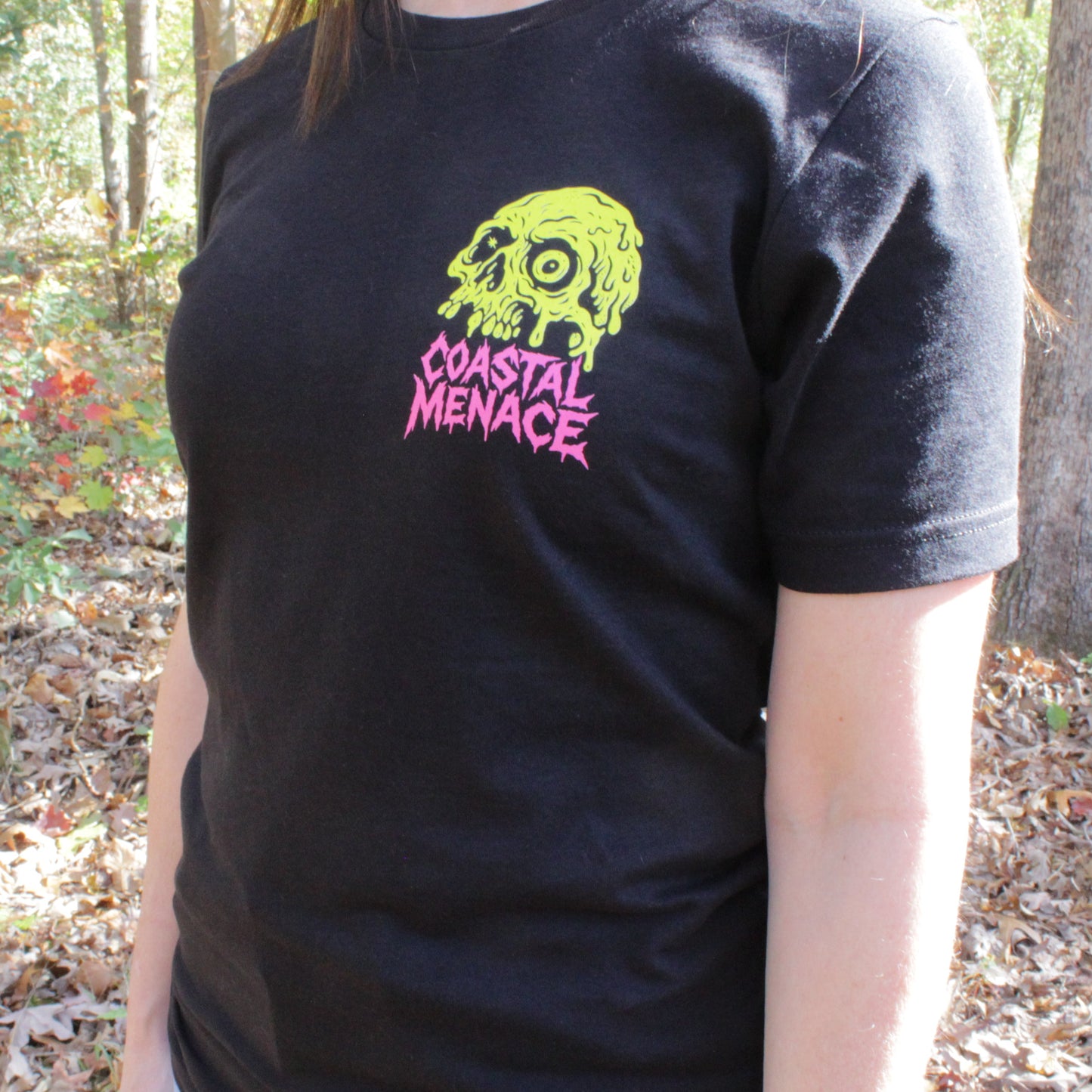 Person wearing a black t-shirt with a skull design in a forest setting