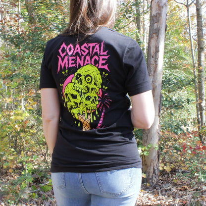 Femal wearing a black t-shirt with 'Coastal Menace' design in a forest setting