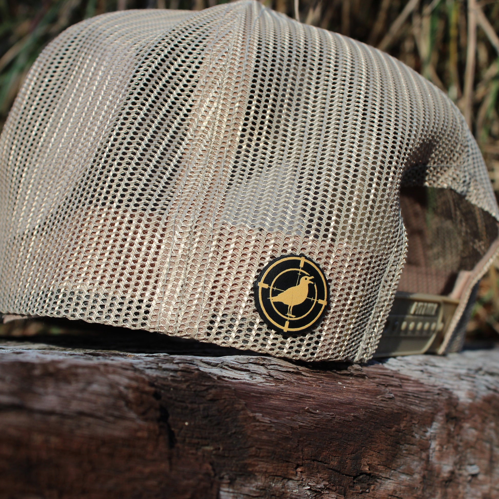 Khaki mesh cap with a logo on a wooden surface with a natural background