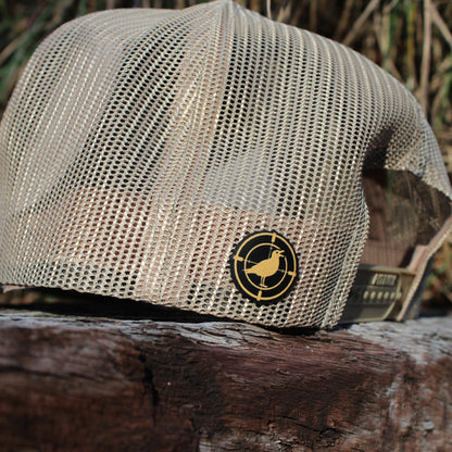 Khaki mesh cap with a logo on a wooden surface with a natural background
