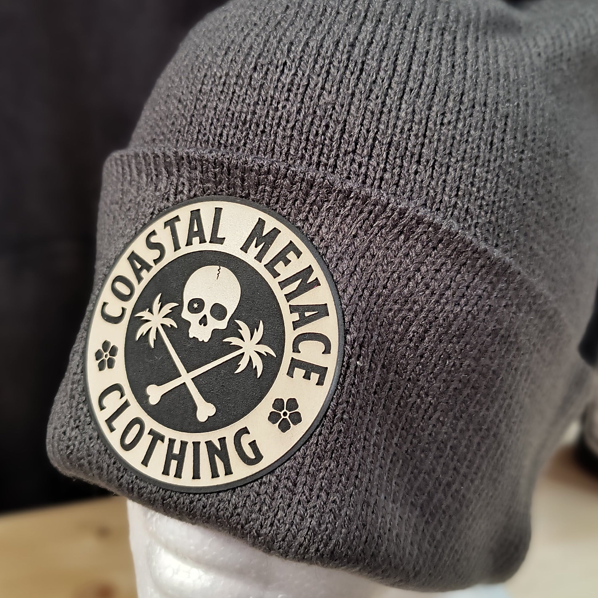 Closeup of grey pom beanie showing round patch detail