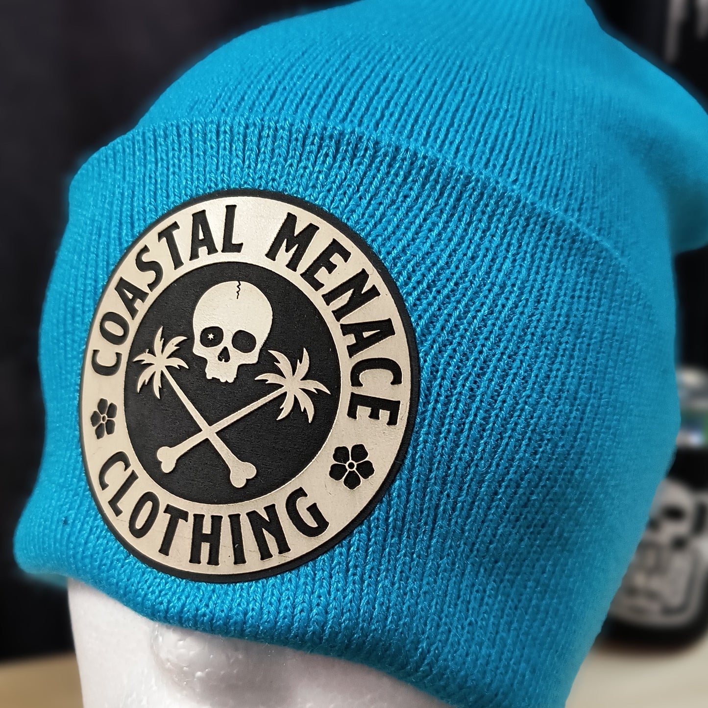 Closeup of neon blue beanie featuring Base Threat patch