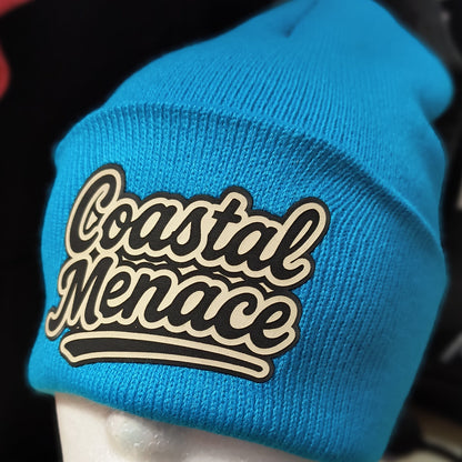 close up of blue beanie showing the retro script Coastal Menace logo patch