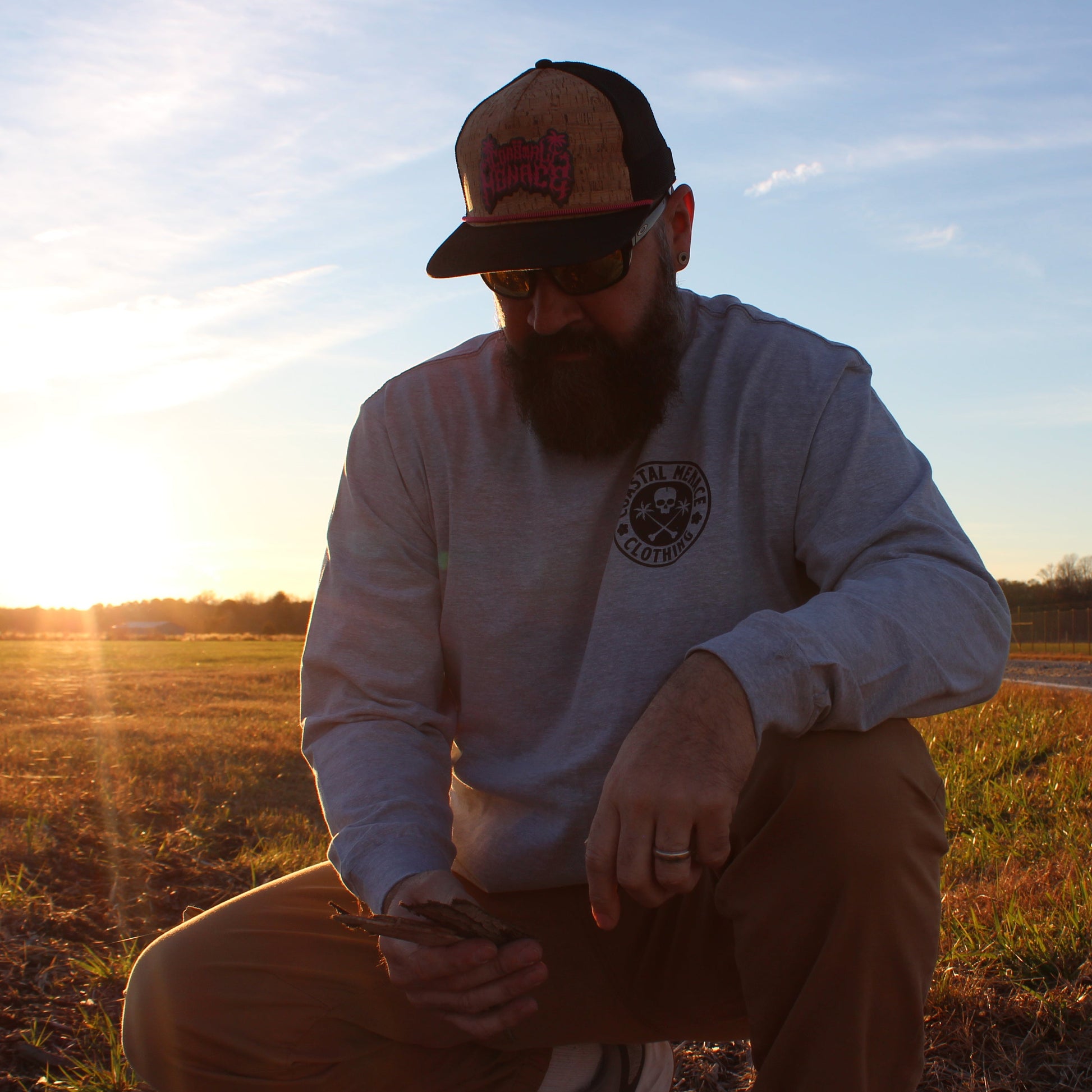 Men’s front view of the Base Threat heather gray long sleeve tee while kneeling outdoors.