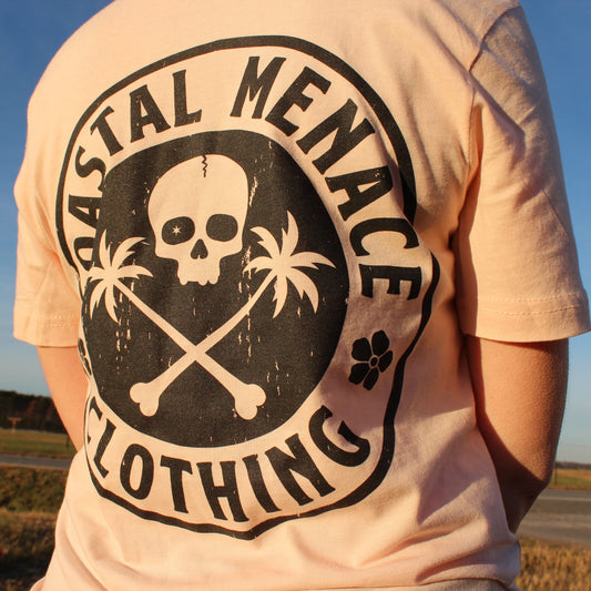 Close-up of the Base Threat pink tee back graphic with skull, crossbones, and palm trees.