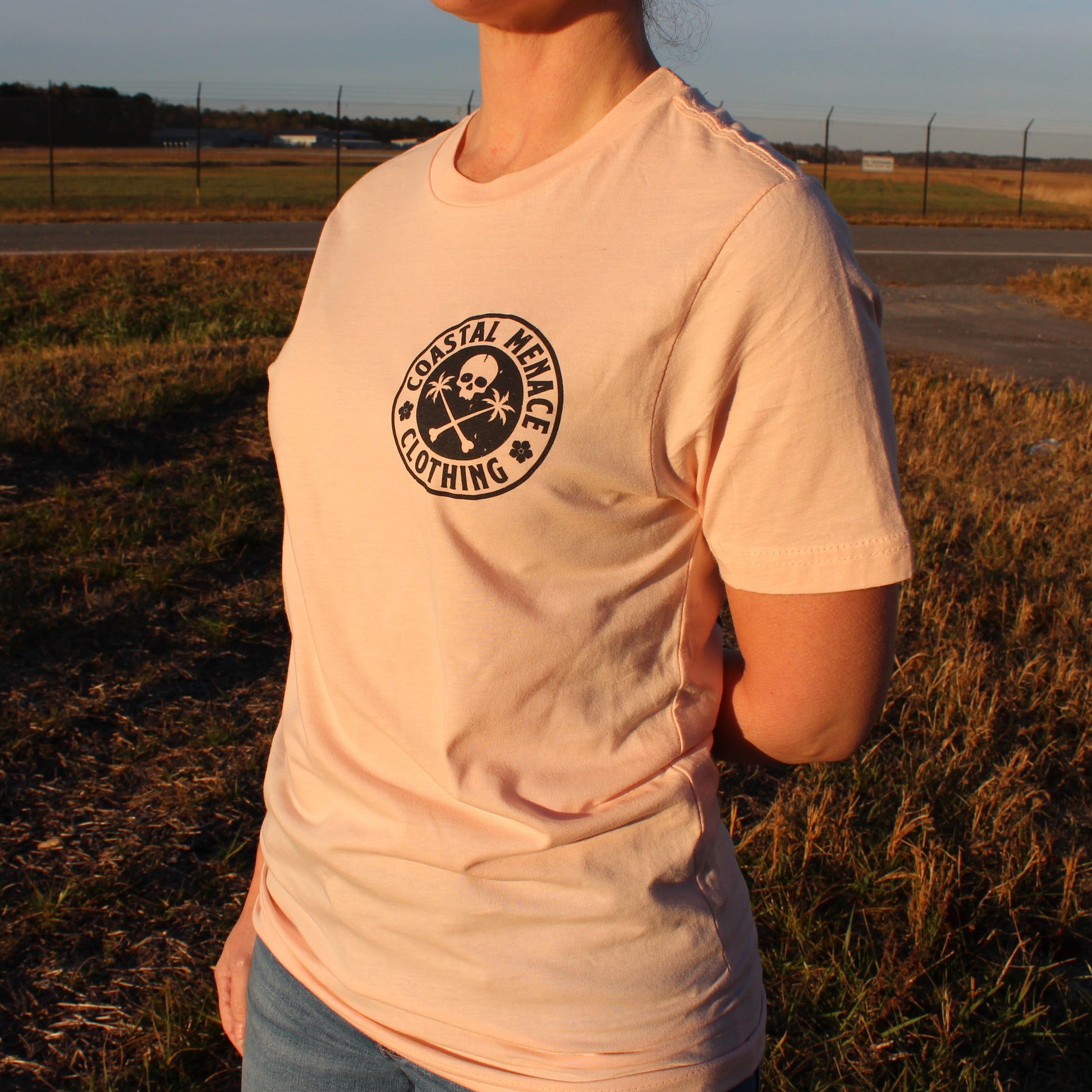 Angled front view of the Base Threat pink t-shirt showing small chest logo.