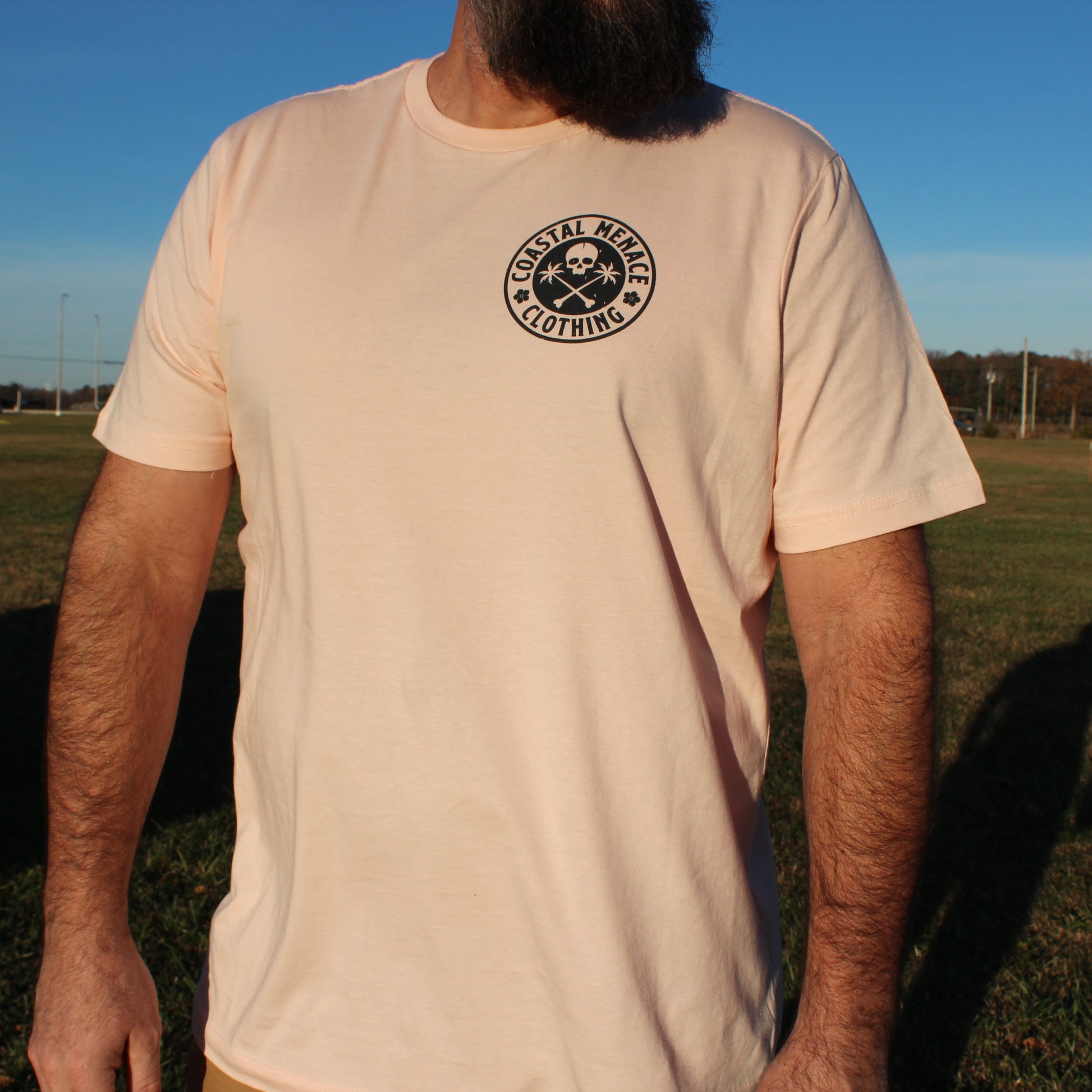 Men’s front view of the Coastal Menace Base Threat pink tee with small chest logo.