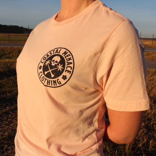 Women’s front view of the Coastal Menace Base Threat pink tee with small chest logo