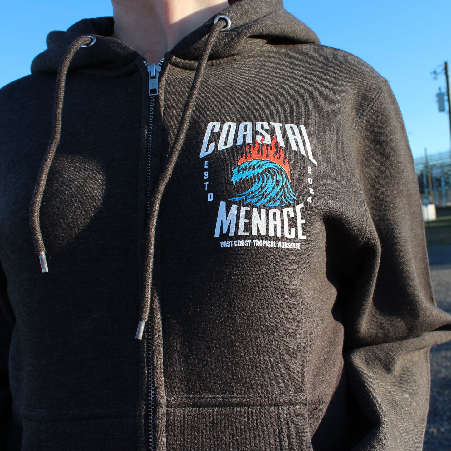 Close-up of the Hot Breaker zip hoodie chest logo on charcoal fabric.