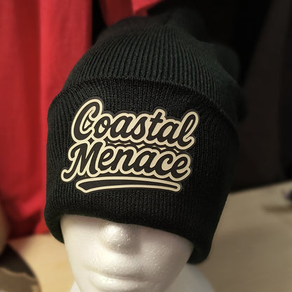 close up of retro script Coastal Menace patch on a black beanie