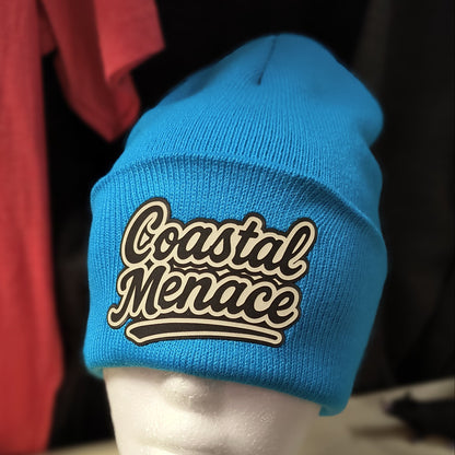 bright blue knit beanie with cream retro script Coastal Menace patch on the cuff
