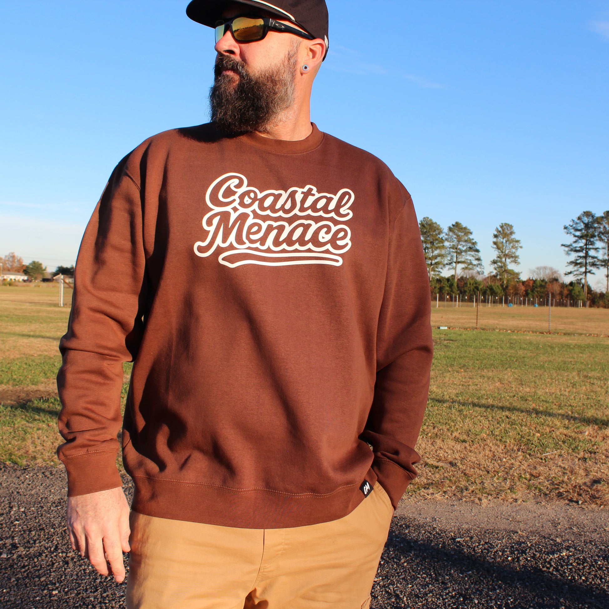man wearing coastal menace retro script crewneck brown front view