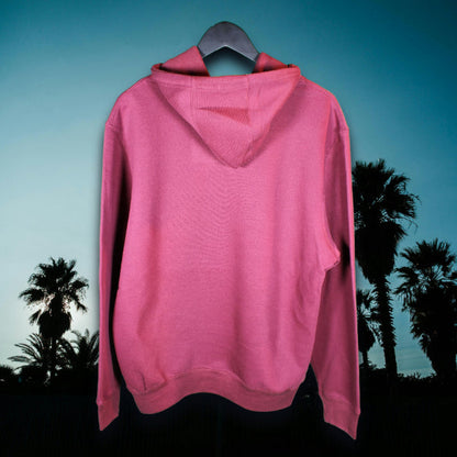 Back view of burgundy-colored Coastal Menace hoodie with no graphic, photographed in front of a dark tropical evening sky with palm silhouettes
