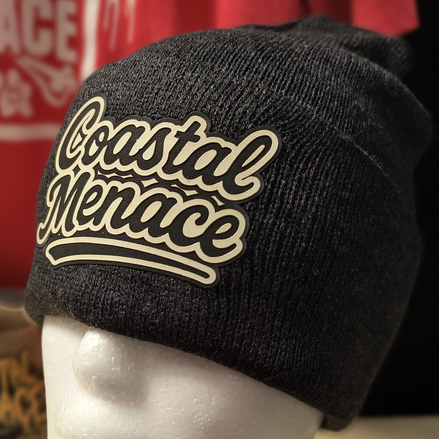 close up of heather grey beanie featuring the retro script Coastal Menace patch