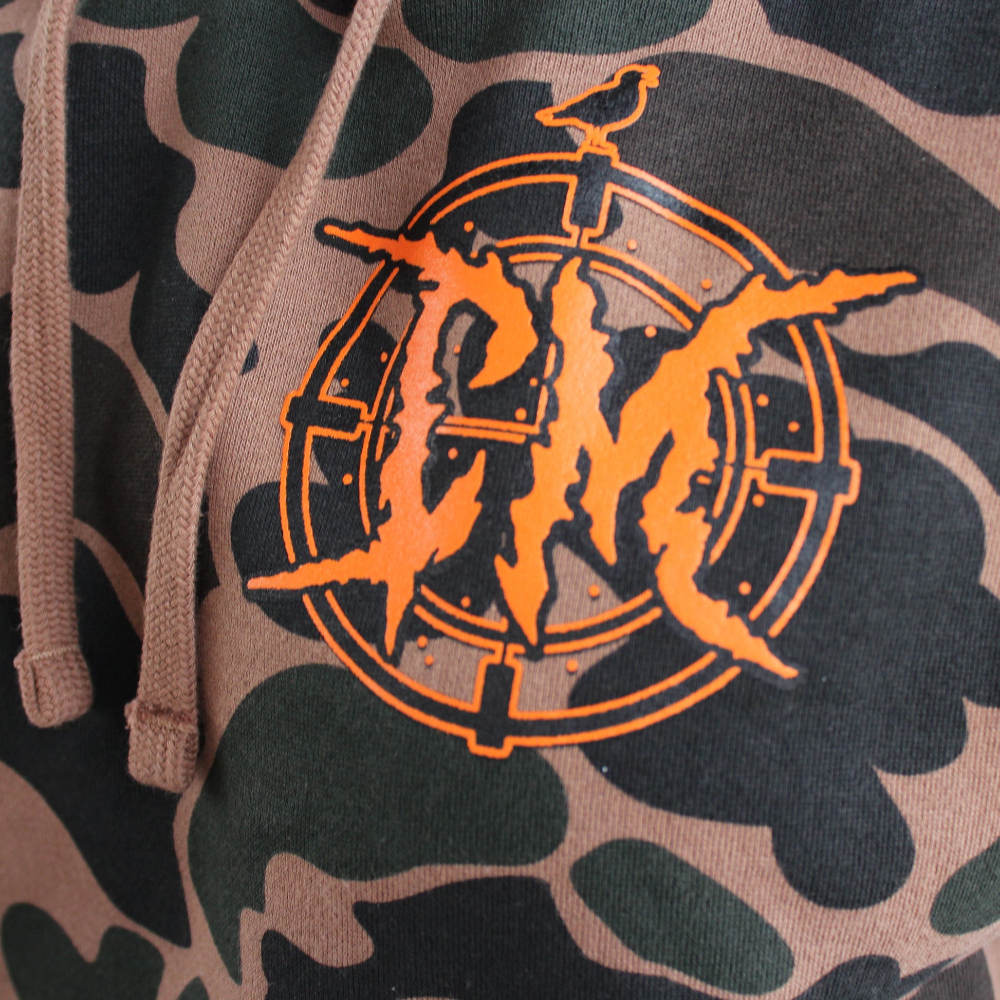 Duck Camouflage hoodie with bright orange logo worn outdoors